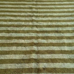 May include: A rectangular rug with alternating horizontal stripes of olive green and light green. The rug has a soft, textured appearance, suggesting a plush or shag design. The stripes are evenly spaced.