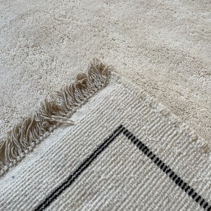 May include: A white rug with a black stripe pattern and fringe along the edge.