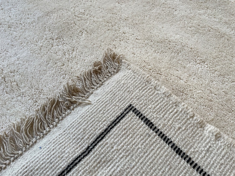 May include: A white rug with a black stripe pattern and fringe along the edge.
