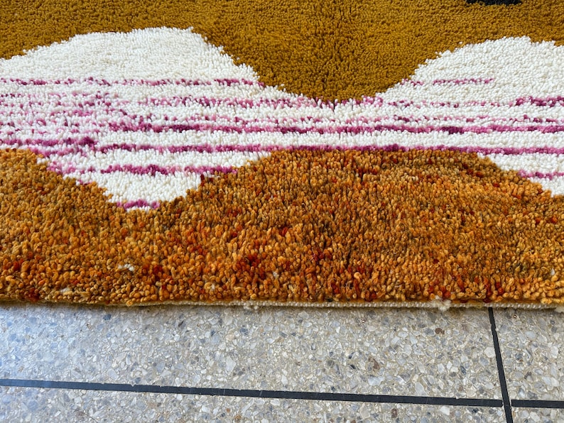 May include: Close-up of a brown, orange, white, and pink shag rug with a geometric pattern. The rug has a thick pile and is made of soft, plush fibers.