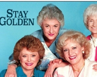 May include: Four women, all with white or gray hair, are smiling and looking at the camera. The women are wearing colorful sweaters and the text "STAY GOLDEN" is written in large, bold letters at the top of the image.