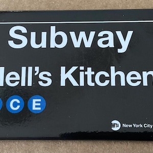 May include: A black rectangular magnet featuring the words "Subway Hell's Kitchen" in white, with the letters A, C, and E in blue circles. The MTA New York City Transit logo is at the bottom.