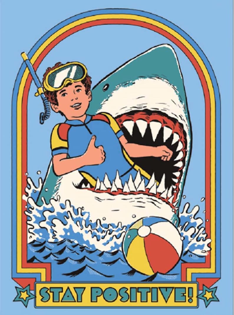 Puede incluir: Una ilustraci&oacute;n de dibujos animados de una persona con un traje de neopreno azul y un snorkel, con el pulgar hacia arriba, dentro de la boca abierta de un tibur&oacute;n. El tibur&oacute;n est&aacute; en el oc&eacute;ano con una pelota de playa. La imagen tiene un arco&iacute;ris sobre el tibur&oacute;n y el texto "STAY POSITIVE!" en la parte inferior.