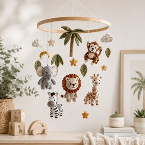 May include: A hanging nursery mobile featuring a circular wooden frame with crocheted figures of a gray elephant, a brown monkey, a tan lion, a giraffe, and a black and white zebra, accented with green palm leaves, yellow stars, and white clouds.