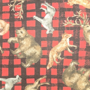 May include: A fabric with a red and black buffalo plaid pattern. The fabric is decorated with illustrations of woodland animals, including bears, deer, foxes, and squirrels. The animals are in shades of brown, tan, and gray.