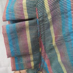 Peut inclure: Gros plan sur un tissu ray&eacute; avec une vari&eacute;t&eacute; de couleurs, notamment le bleu, le jaune, le rouge et le violet. Le tissu a une apparence textur&eacute;e et tiss&eacute;e.