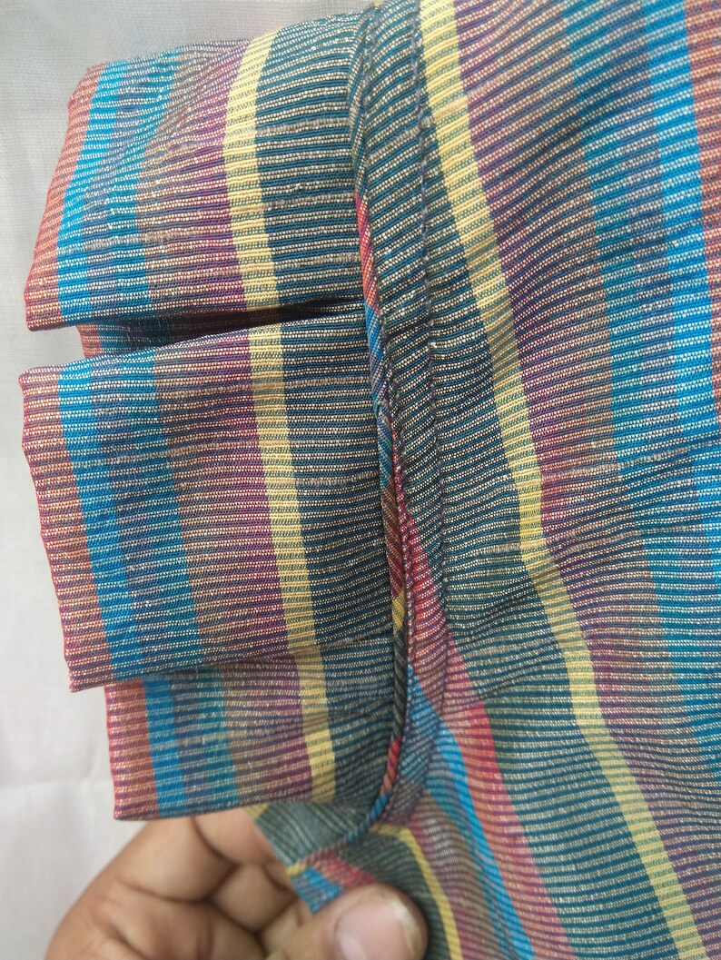 Peut inclure: Gros plan sur un tissu ray&eacute; avec une vari&eacute;t&eacute; de couleurs, notamment le bleu, le jaune, le rouge et le violet. Le tissu a une apparence textur&eacute;e et tiss&eacute;e.