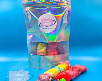 May include: A bag of freeze-dried treats called "Cosmic Crunch" with a rainbow swirl design. The bag is iridescent and has a pink logo. Two rainbow swirl treats are outside the bag, one with a red and green eyeball.