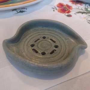May include: A light blue ceramic soap dish with a circular design and drainage holes.