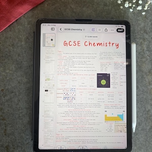 Op de afbeelding: Een zwarte tablet met een digitaal document getiteld GCSE Chemistry, voorzien van gedetailleerde educatieve aantekeningen, tabellen en diagrammen over atoomstructuur, elementen en chemische bindingen, met een witte stylus aan de zijkant.