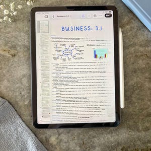 Può includere: Un tablet che mostra un documento digitale intitolato Business 3.1 con una mappa mentale e un grafico a barre. Lo schermo presenta testo su concetti aziendali e una barra laterale con miniature delle pagine. Uno stilo bianco è fissato al lato.