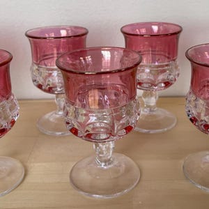 May include: Set of six clear glass stemmed shot glasses with a ruby red rim and a textured pattern.
