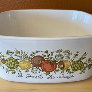 May include: White ceramic baking dish with a green, brown, and yellow floral design featuring vegetables and the text "Le Persil La Sauge".