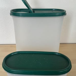May include: Two oval-shaped plastic containers with green lids. The larger container has a hinged lid with a flip-top opening. The smaller container has a solid lid.