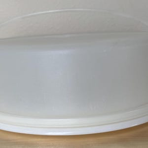 May include: A white plastic cake carrier with a handle. The carrier has a clear lid and a white base.