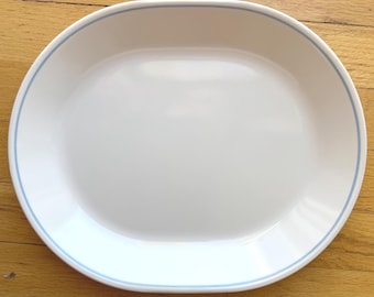 May include: A white oval serving platter with a light blue rim.