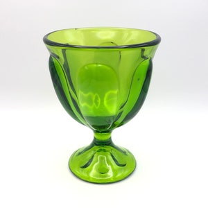 May include: A green glass goblet with a fluted design and a round base.