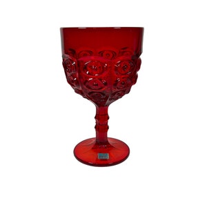 May include: A red glass goblet with a textured, bubble-like design. The goblet has a tall, slender stem and a round base.