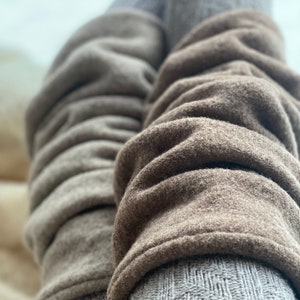 Könnte beinhalten: Ein Paar braune und graue gestrickte Beinstulpen. Die Beinstulpen sind aus einem weichen, flauschigen Material gefertigt und haben eine gerippte Struktur.