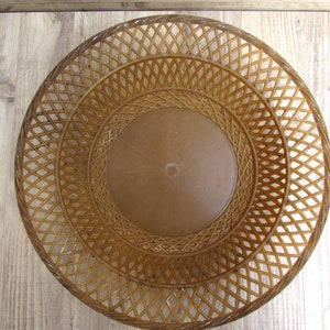 May include: A brown woven plastic basket with a circular shape and a lattice design.