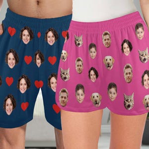 May include: A pair of blue and pink shorts with a pattern of faces and hearts. The shorts are made of a soft, comfortable fabric and have an elastic waistband.