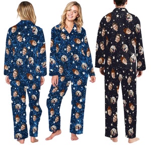 Op de afbeelding: Een blauwe pyjama met een witte ster- en gezichtsprint. De pyjama heeft lange mouwen en een knoopsluiting.