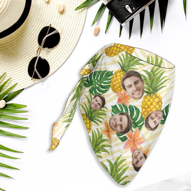 May include: A yellow and green bandana with a pineapple and tropical leaf pattern.  The bandana has multiple faces printed on it.