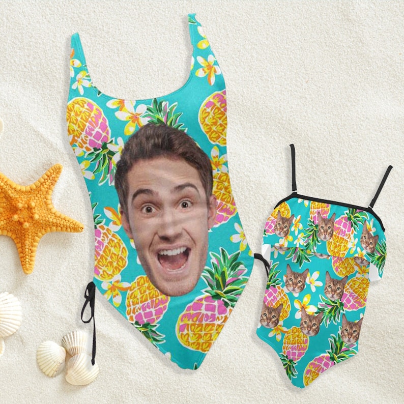 Peut inclure: Un maillot de bain une pi&egrave;ce sur fond bleu sarcelle avec un motif d'ananas jaunes et roses et de fleurs blanches, arborant une grande photo d'un visage souriant, accompagn&eacute; d'un maillot de bain assorti plus petit avec des t&ecirc;tes de chat.
