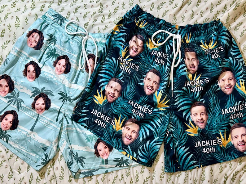 May include: Two pairs of swim shorts with drawstring waistbands. One pair is light blue with a palm tree pattern and repeating faces. The other pair is dark green with a tropical leaf pattern, repeating faces, and the text Jackie's 40th.