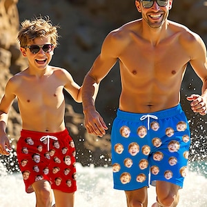 May include: Two people wearing matching swim trunks with a pattern of repeated faces. The trunks are red and blue. The people are smiling and wearing sunglasses.
