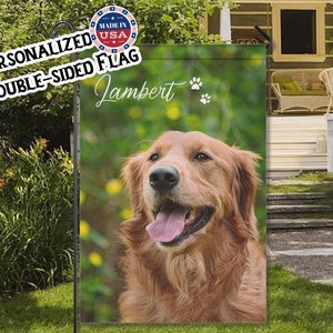 May include: A double-sided garden flag with a golden retriever dog. The flag displays the name "Lambert" in script, paw prints, and the text "Personalized Double-Sided Flag" and "Made in USA". The dog has a pink tongue and is set against a green background.