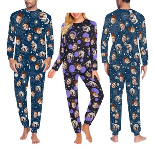 Op de afbeelding: Een set van drie pyjama's met een blauwe, paarse en zwarte achtergrond met een herhalend patroon van sterren, manen en gezichten. De gezichten zijn van mensen en honden.