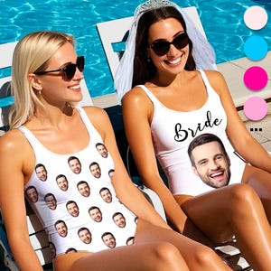 May include: Two white swimsuits with custom face prints. One swimsuit says "Bride" in black script and features a man's face. The other swimsuit is covered in a pattern of the same man's face. Both women are wearing sunglasses.