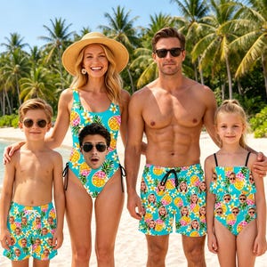 May include: A collection of matching swimwear featuring a bright turquoise background with a repeating pattern of yellow pineapples, white flowers, and custom printed faces. The set includes a one-piece swimsuit, two pairs of swim trunks, and a tankini.