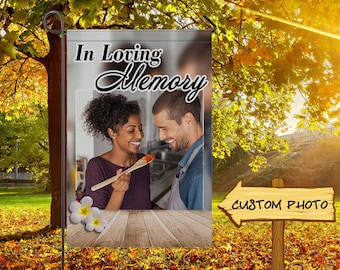 May include: A garden flag with the words "In Loving Memory" above a photo of a couple. The flag has a wooden sign that says "Custom Photo". The background is a sunny outdoor scene with trees and fall foliage.