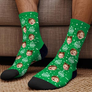 May include: Green socks with the text "BEST DAD EVER" and photos of children. The socks have black toes and heels, and white star accents. A unique gift idea.