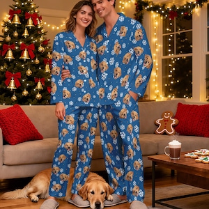 May include: Matching blue pyjama sets featuring a repeating pattern of golden retriever faces and white snowflakes. The long-sleeved button-down shirts have notched collars, and the long trousers have a straight-leg fit with an all-over print design.