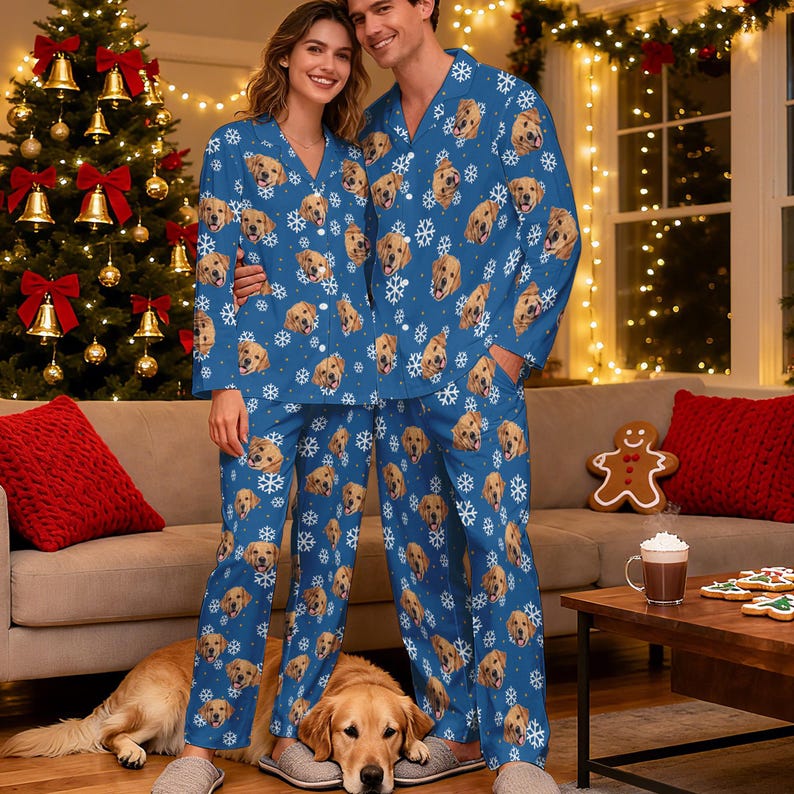 May include: Matching blue pyjama sets featuring a repeating pattern of golden retriever faces and white snowflakes. The long-sleeved button-down shirts have notched collars, and the long trousers have a straight-leg fit with an all-over print design.