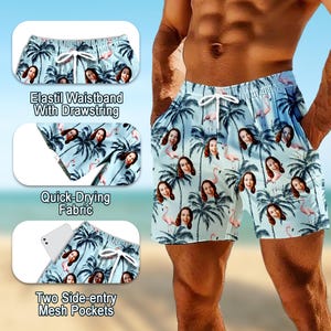 May include: Light blue swim shorts featuring a repeating pattern of palm trees, pink flamingos, and a woman's face. The shorts include an elastic waistband with a white drawstring, quick-drying fabric, and two side-entry mesh pockets.