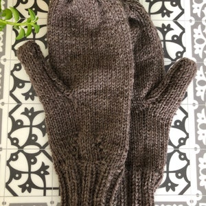 Pu&ograve; includere: Un paio di guanti senza dita di lana marroni con polsino a coste.