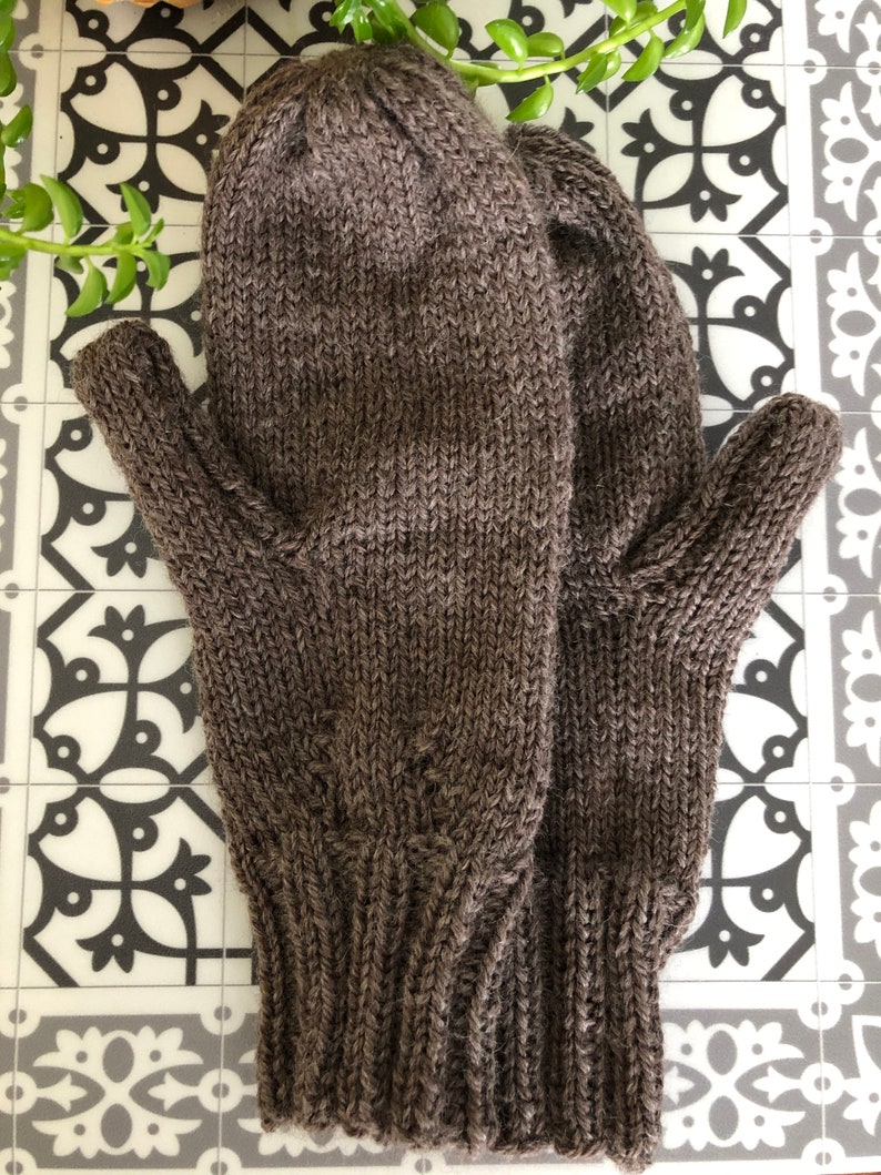 Pu&ograve; includere: Un paio di guanti senza dita di lana marroni con polsino a coste.