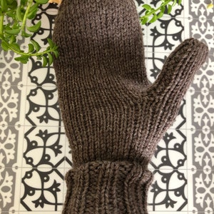 Pu&ograve; includere: Un guanto di lana marrone con un polsino ripiegato. Il guanto &egrave; fatto di un filato spesso e testurizzato.