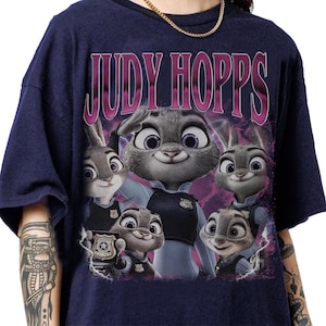 May include: Navy blue t-shirt featuring the text "JUDY HOPPS" in pink and a graphic of Judy Hopps and other characters from the movie Zootopia. The design includes the characters in police uniforms.
