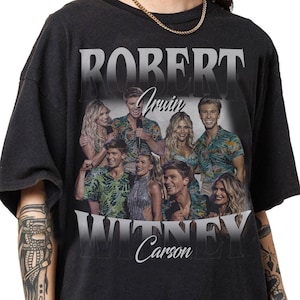 May include: Black t-shirt featuring a group photo with the names "ROBERT IRWIN" and "WITNEY Carson" in white text. The photo shows several people in colorful shirts and dresses.