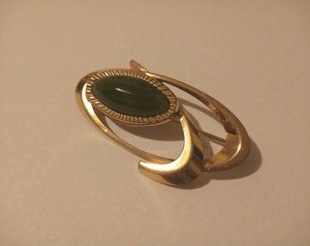 Oval gold tone brooch with green stone