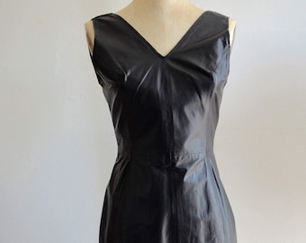 Vestido militar de cuero de los años 80, sin mangas, con paneles, negro, escote pronunciado, estilo secretaria rockera.