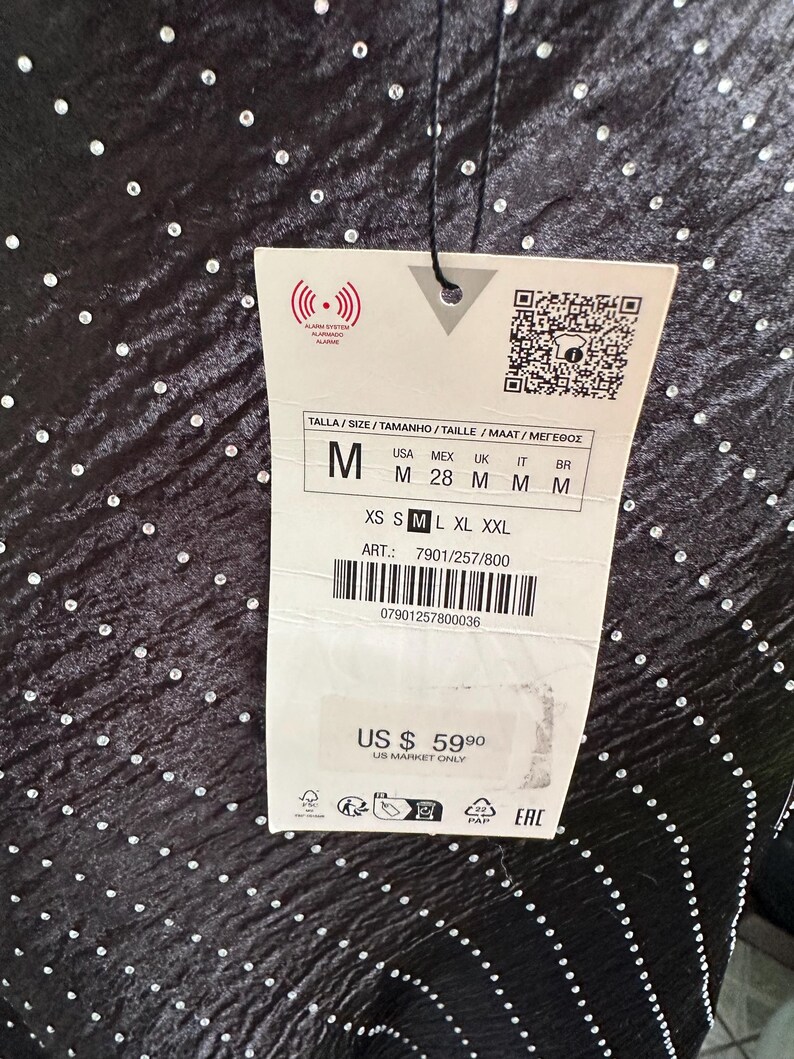 Puede incluir: Vestido negro con un patr&oacute;n de puntos brillantes. La etiqueta dice "M" para el tama&ntilde;o y "US $ 59.90" para el precio. La etiqueta tambi&eacute;n incluye el texto "US Market Only".