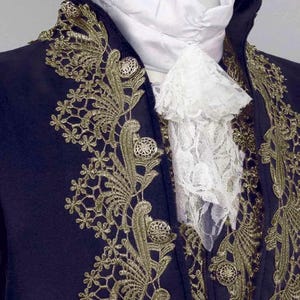 May include: A navy blue jacket with gold embroidery and a white lace cravat. The jacket has a high collar and a button-up front.