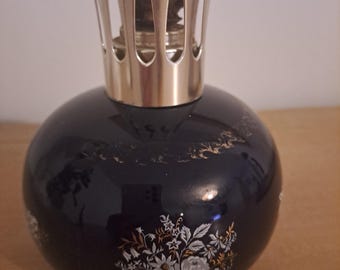 May include: A blue ceramic oil burner with a silver top and a floral design. The burner has a round body and a decorative top with cutouts.