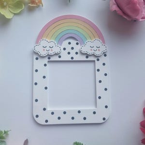 May include: White light switch cover with a rainbow, two clouds with smiley faces, and black polka dots.